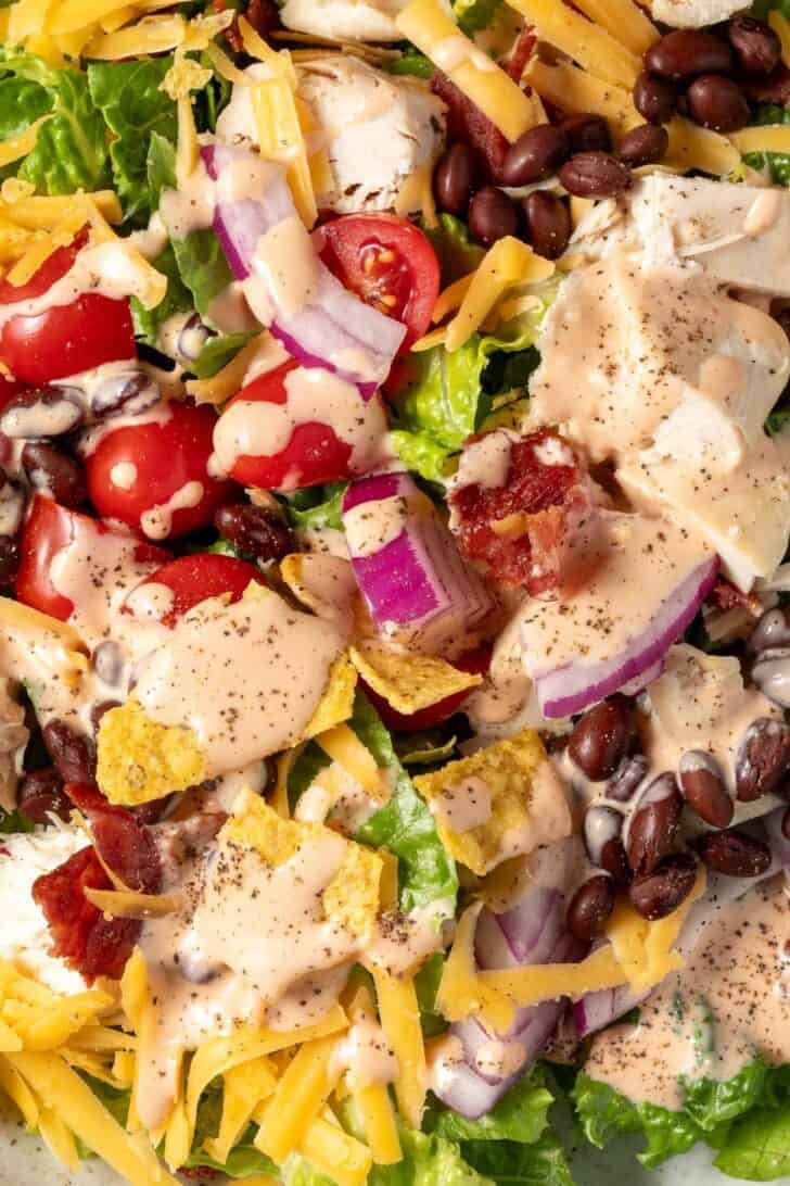 A bowl filled with a tossd green salad tossed with Southwest Salad Dressing.