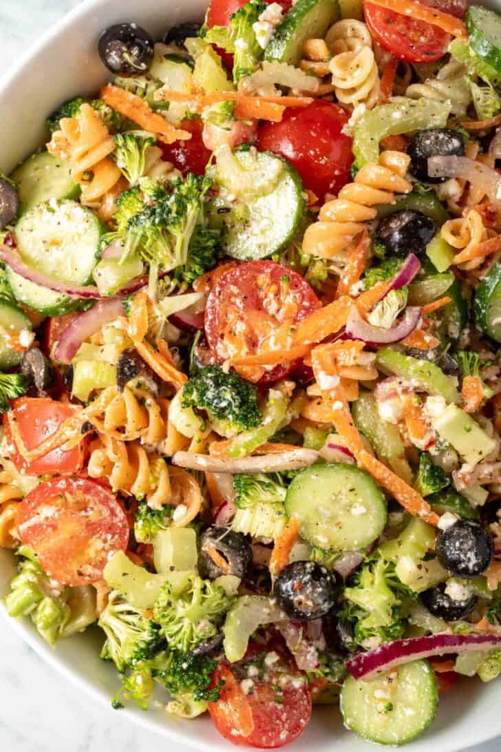 A white bowl filled with Easy Summer Pasta Salad (noodles and crispy vegetables tossed in a creamy vinaigrette).