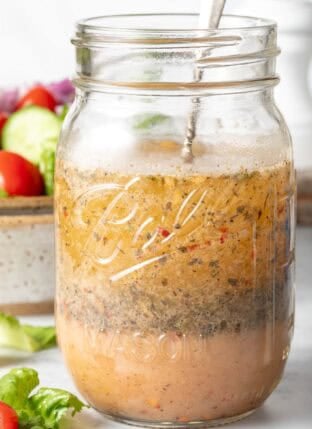 A clear glass mason jar filled with Zesty Italian Salad Dressing.