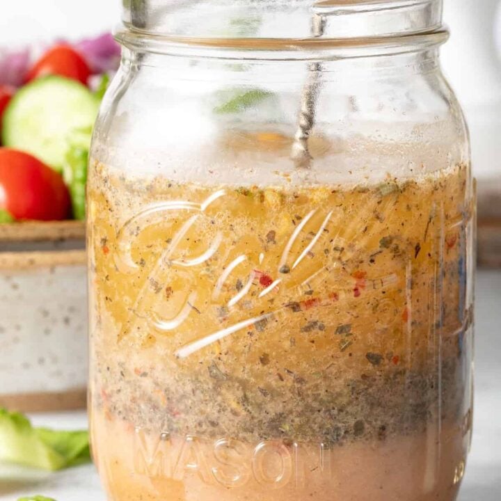 A clear glass mason jar filled with Zesty Italian Salad Dressing.