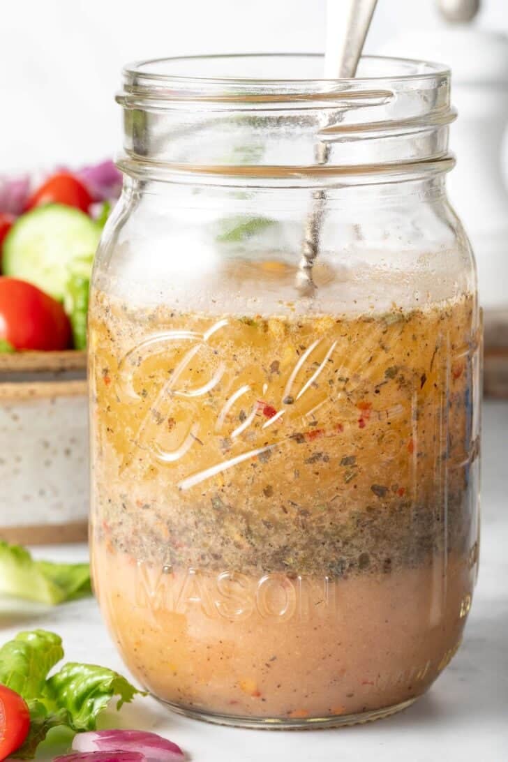 A clear mason jar filled with Zesty Italian Salad Dressing.