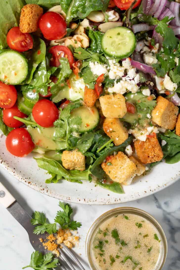 A plate filled with green salad tossed with Asian Salad Dressing.