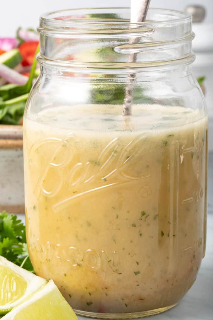 A clear mason jar filled with citrus Asian Ginger Salad Dressing.