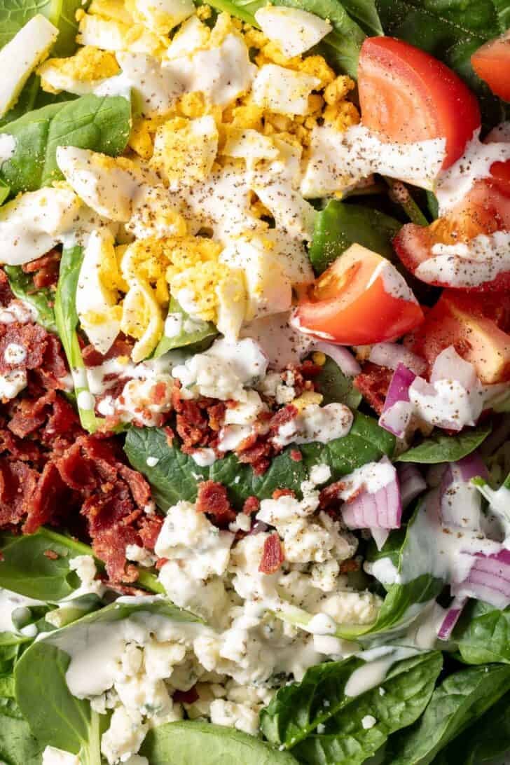 A white plate filled with Spinach Bacon Salad.