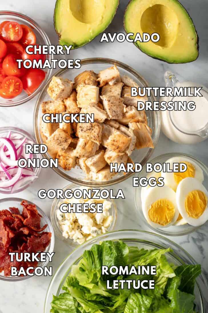 Clear glass bowls filled with hard boiled eggs, Romaine lettuce, turkey bacon, red onion and tomatoes.
