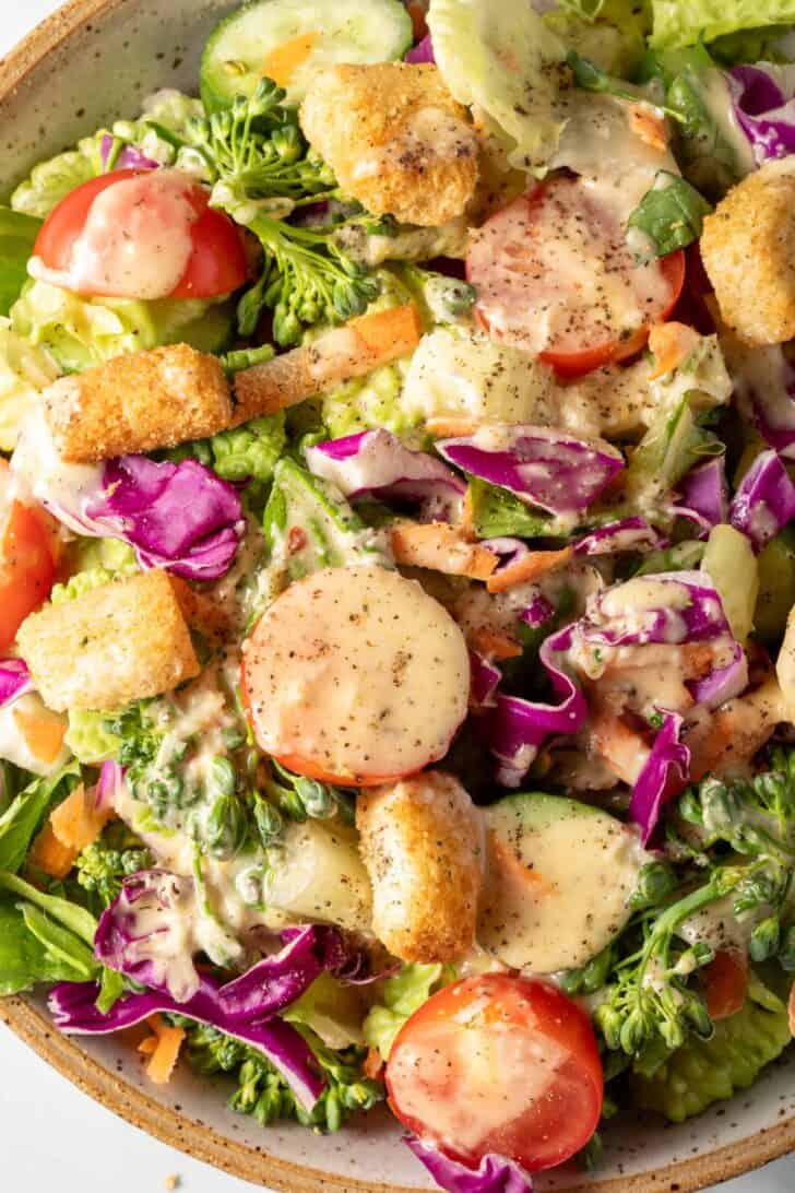 A white bowl filled with salad tossed with Creamy Vinaigrette,