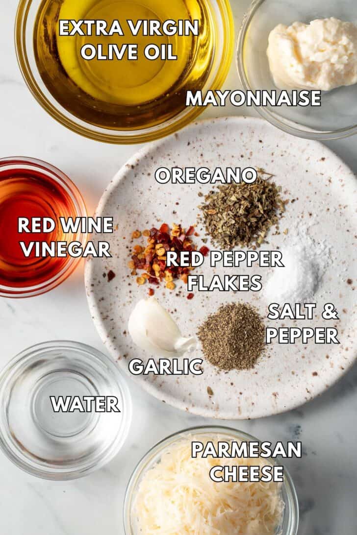 Clear glass bowls filled with olive oil, red wine vinegar, water, mayonnaise and Parmesan cheese.