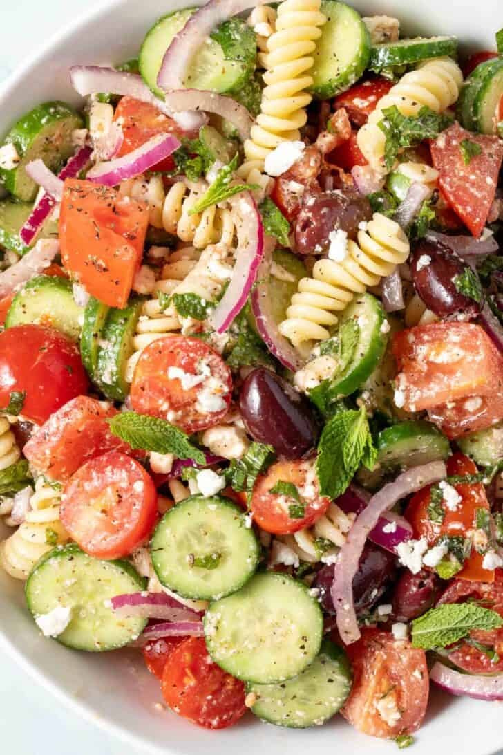A white bowl filled with Greek Pasta Salad.