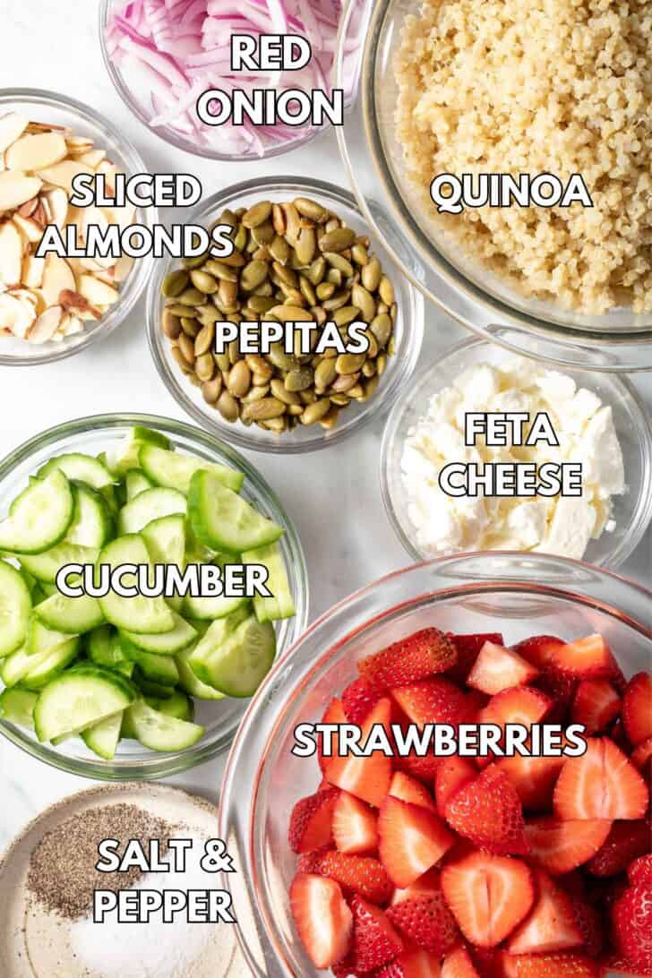 Clear glass bowls filled with fruit, cucumber, feta cheese, sliced almonds and red onion.