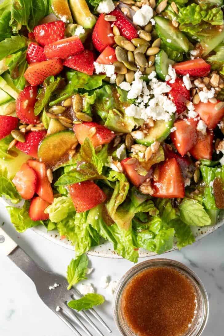 A bowl of green salad tossed with Pomegranate Salad Dressing.