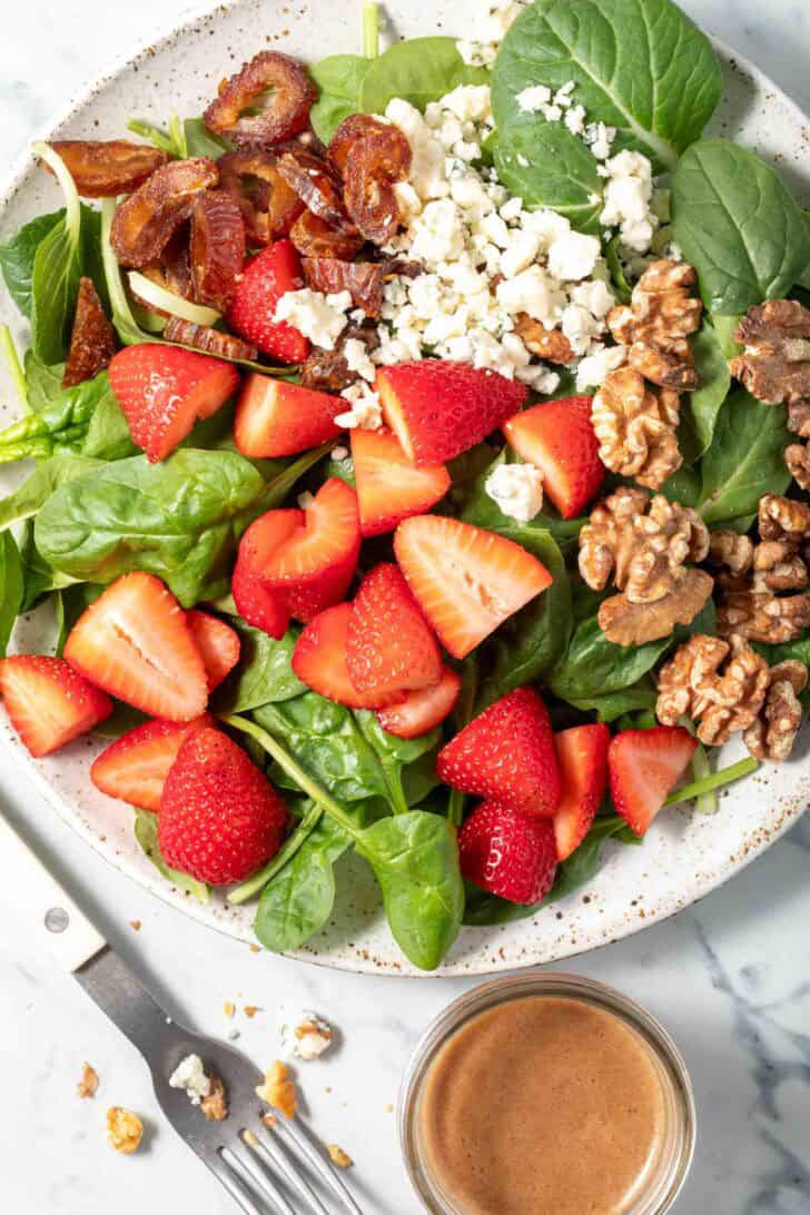 A white plate filled with Spinach Strawberry Salad.