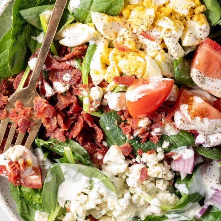 A white plate filled with Bacon Spinach Salad.
