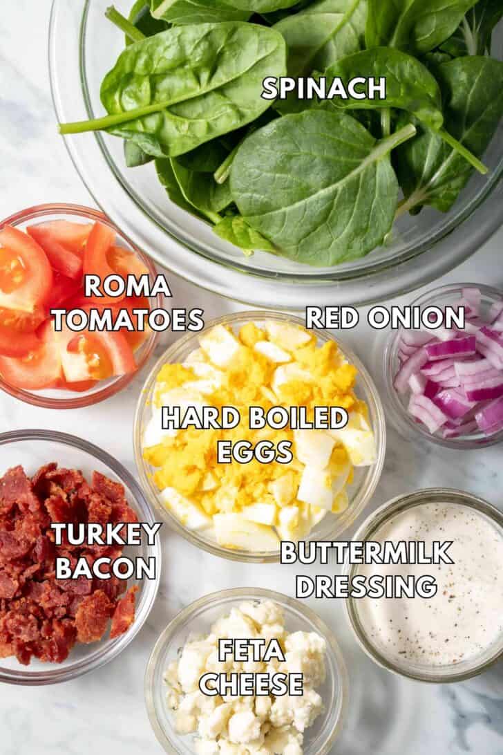 Clear glass bowls filled with mixed greens, tomatoes, cheese, onions and dressing.