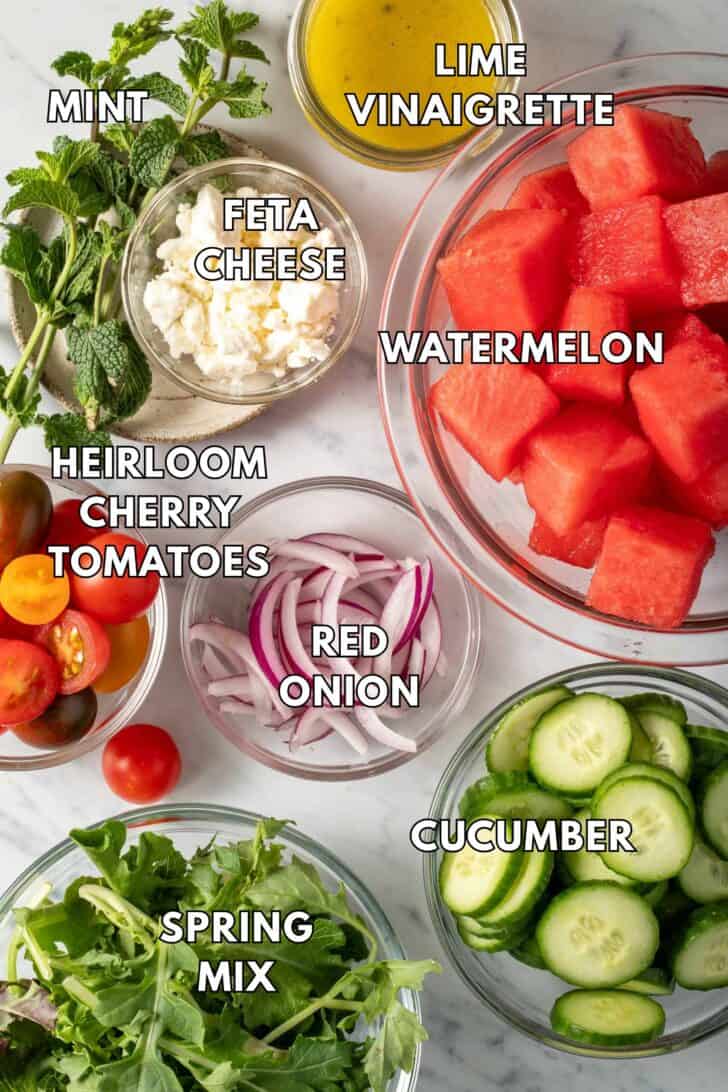 Clear glass bowls filled with fruit, spring mix, cherry tomatoes, red onion, vinaigrette and cheese.