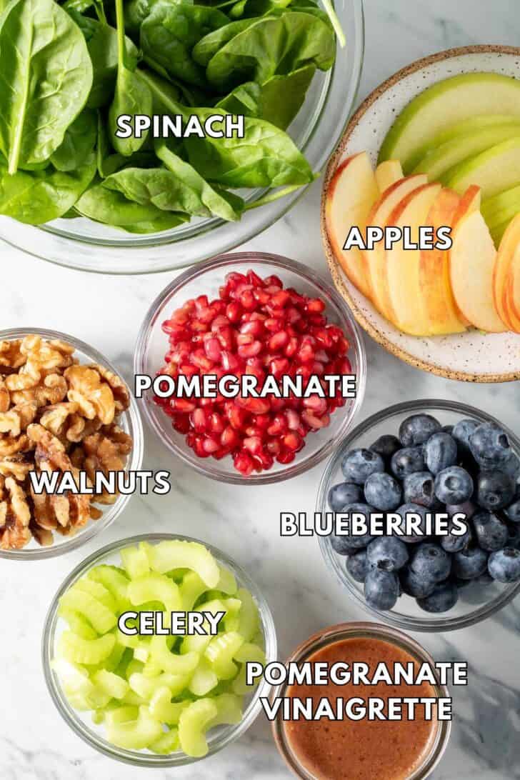Clear glass bowls filled with fruit, celery, nuts, greens and dressing.