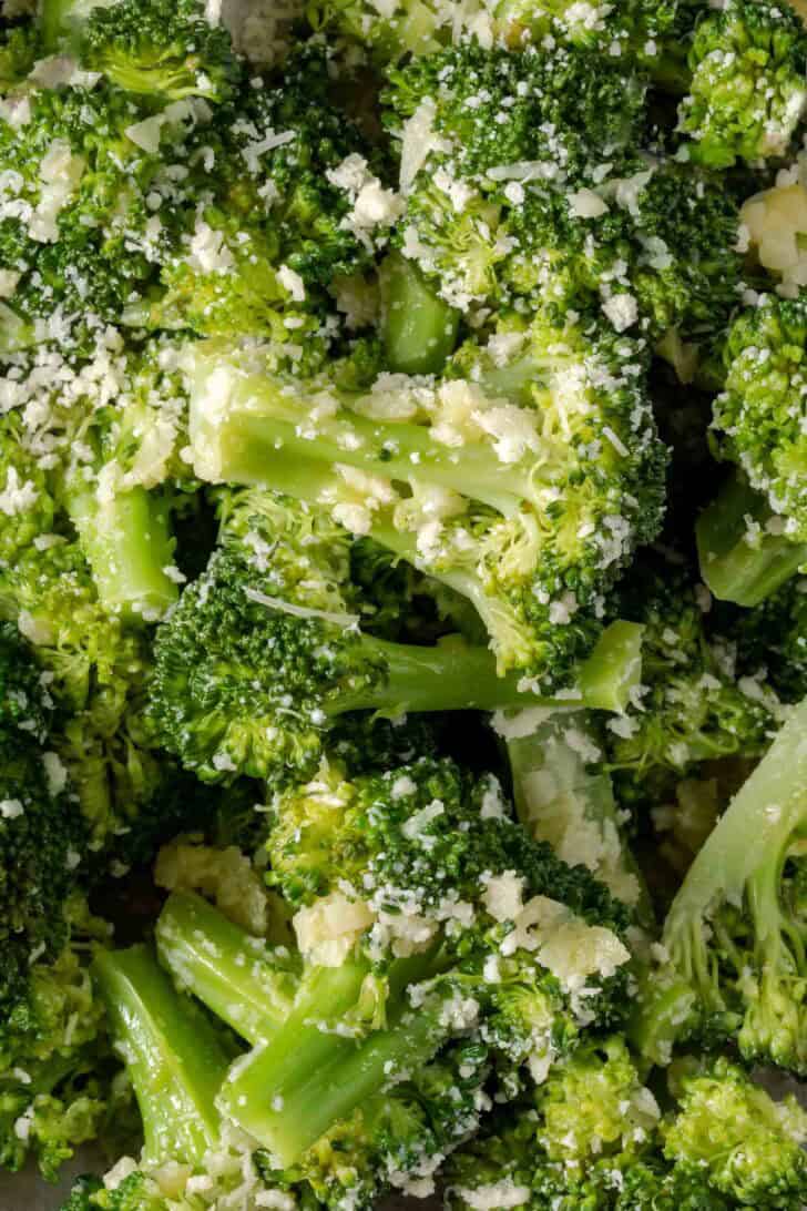 Steamed broccoli tossed in Parmesan cheese in a bowl.