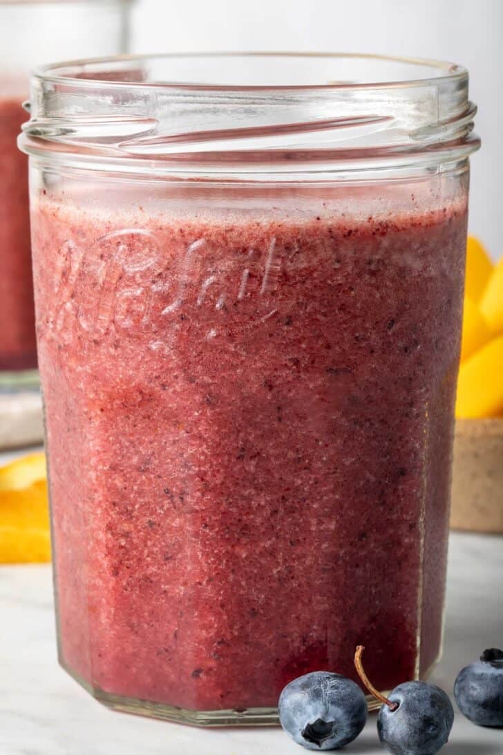 Mango and Blueberry Smoothie in a clear drinking glass.
