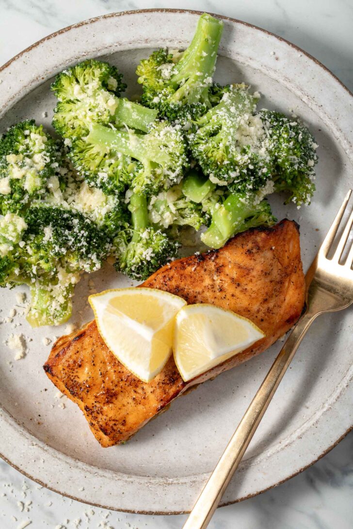 Steamed broccoli on a plate with grilled salmon.
