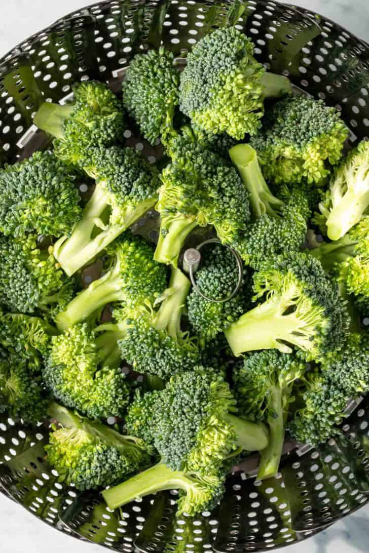 Raw broccoli in a steamer basket.