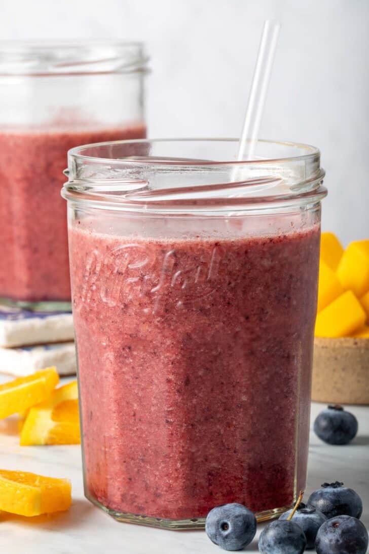 Banana Mango Blueberry Smoothie in two clear drinking glasses.