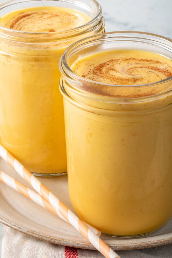 Two mango lassi drink in mason jars.