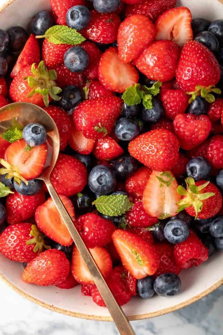 A Summer Berry Salad in a bowl with a spoon in it.