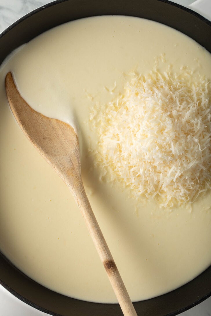 Homemade Alfredo Sauce in a pan with a wooden spoon.