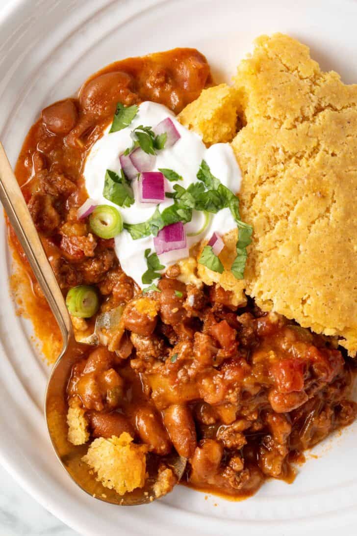 Chili Cornbread Casserole in a white bowl with a spoon.