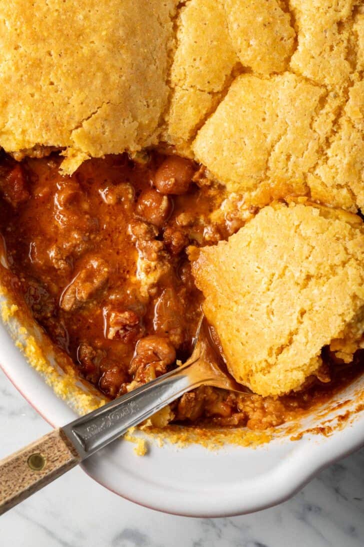 Chili Cornbread Casserole in a baking dish with a serving spoon.