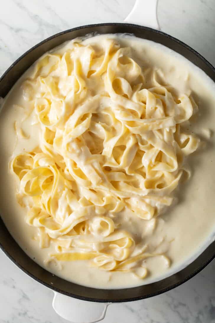 Fettuccine Alfredo in a white skillet.