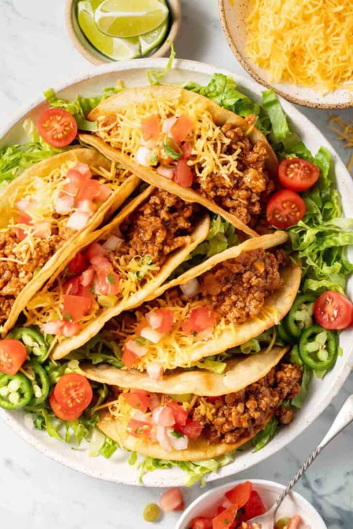 Ground turkey hard shell tacos on a white plate.