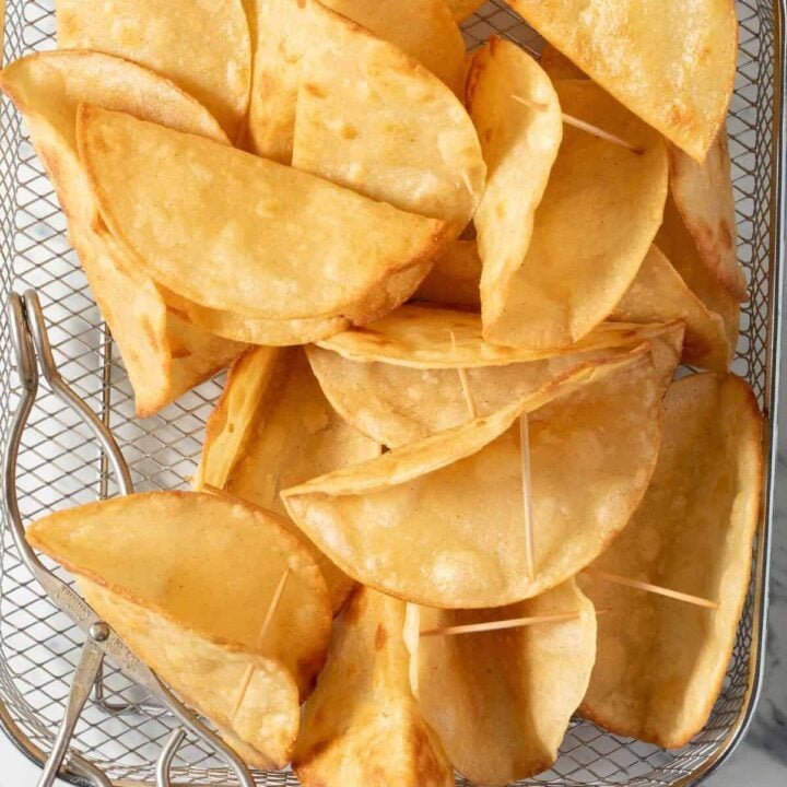 Several homemade Hard Taco Shells in a wire basket.