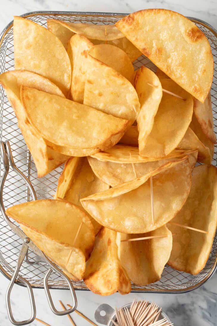 Homemade hard taco shells in a wire basket.