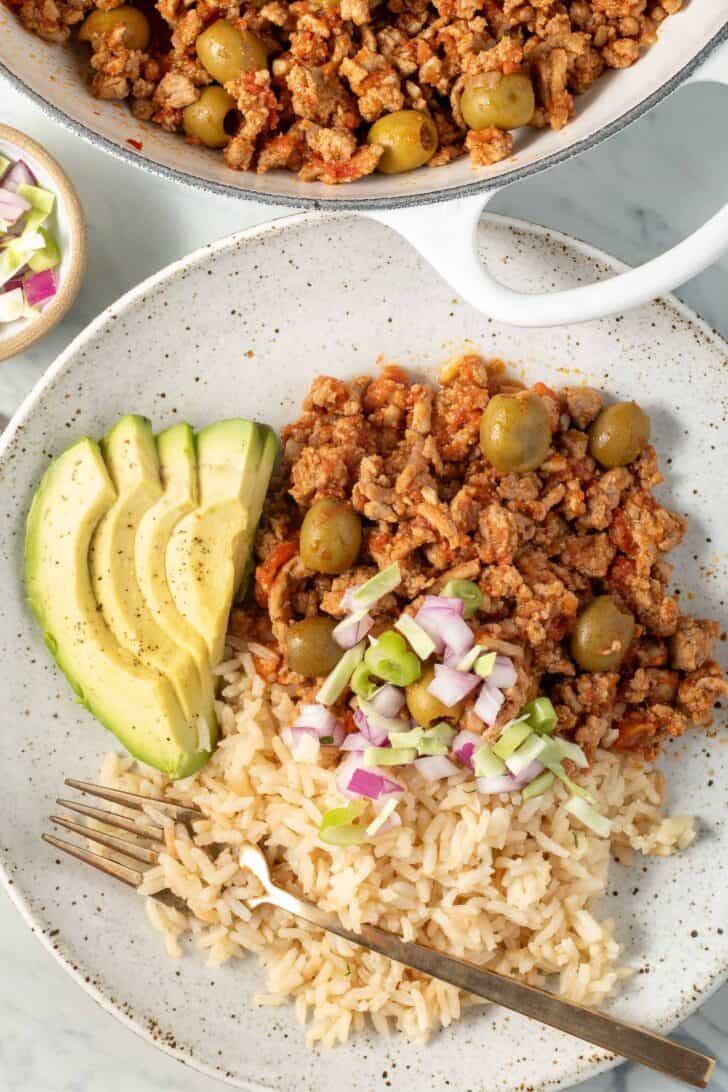 Turkey Picadillo and white rice on a plate with a fork.