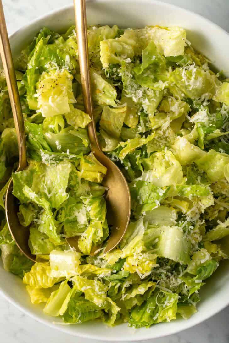 Lemon Parmesan Salad in a white bowl with golden salad servers.