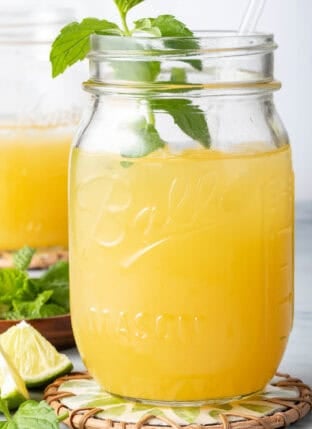 Mango Tea in a clear glass mason jar with a straw.