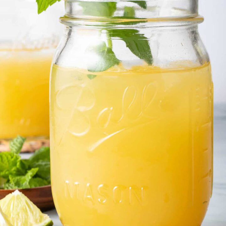 Mango Tea in a clear glass mason jar with a straw.