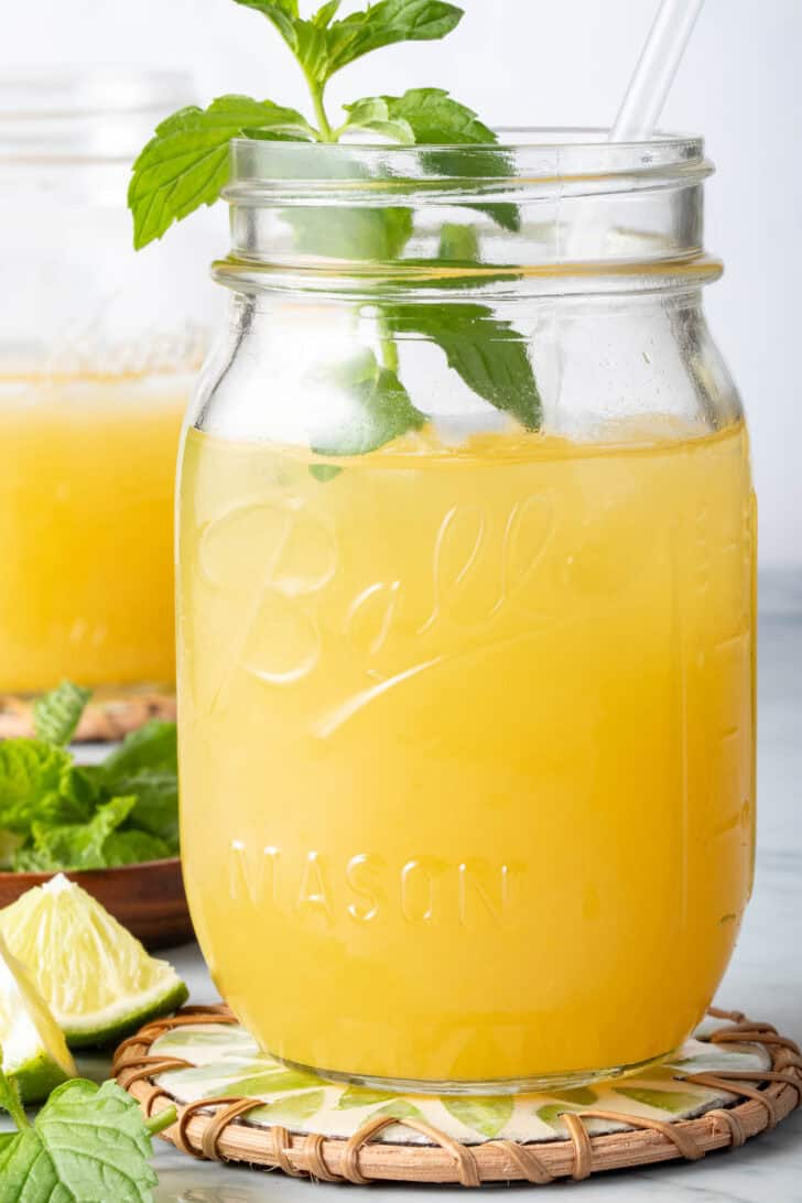 Mango Green Tea in a clear mason jar with a straw.