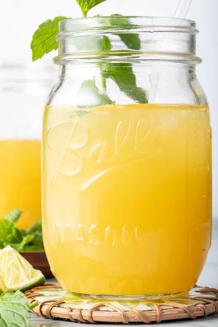 Mango Iced Tea in a clear glass mason jar with a straw.