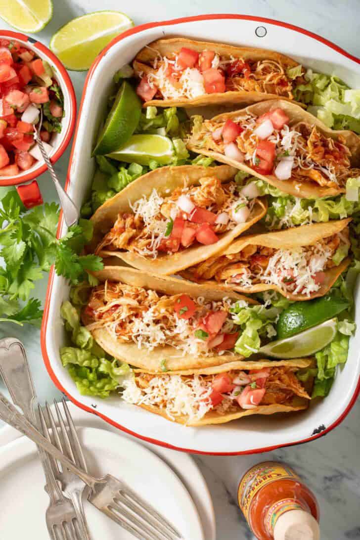 Pulled chicken tacos in a white tray.