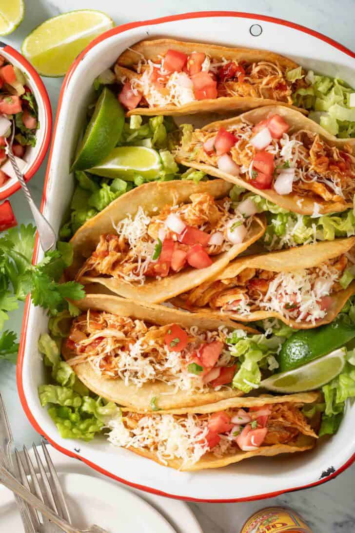 Pulled chicken tacos on a white tray.