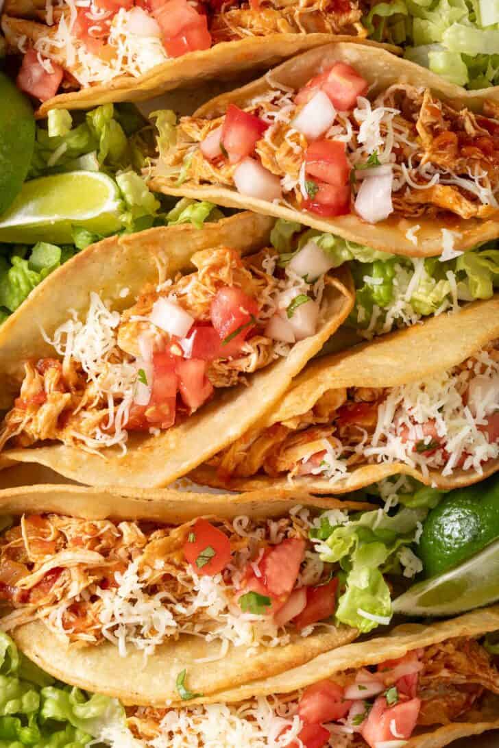 Shredded chicken tacos on a white tray.