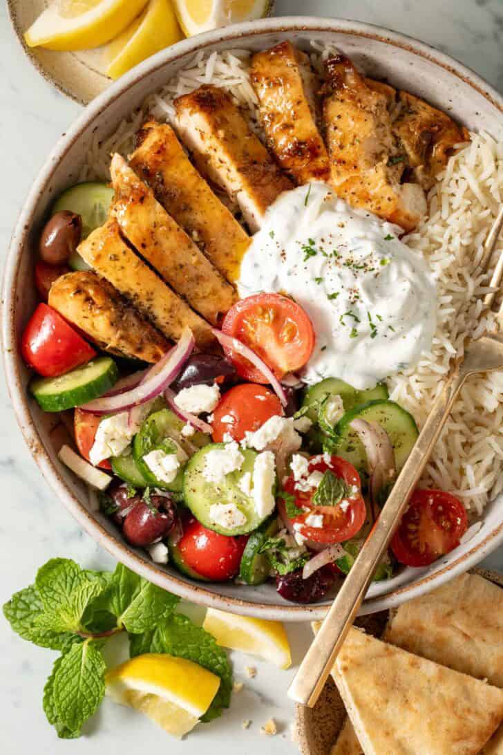 Greek Chicken Bowls Greek Chicken Bowl (with sliced marinated chicken, cucumber salad, basmati rice and dill sauce).