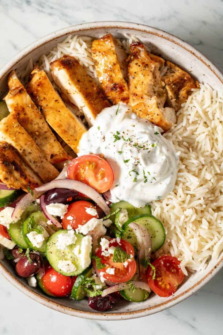 Greek Chicken Bowls Greek Chicken Bowl (with marinated chicken, cucumber salad, Basmati rice and dill sauce).