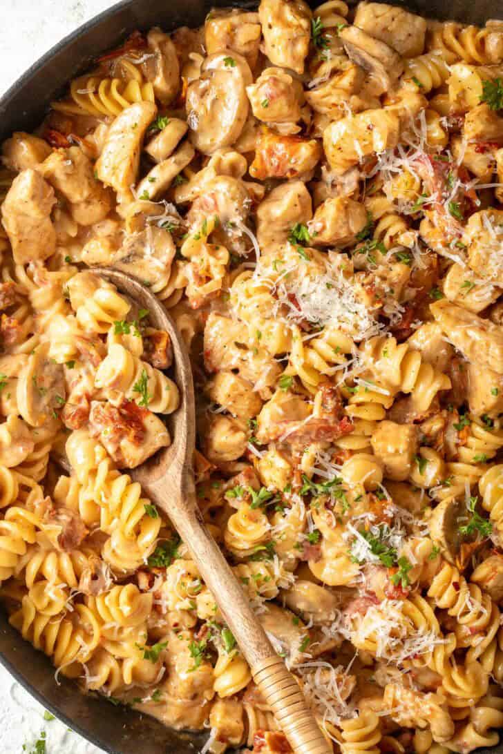How to Make Marry Me Chicken Pasta Marry Me Chicken Pasta in a skillet with a wooden serving spoon.