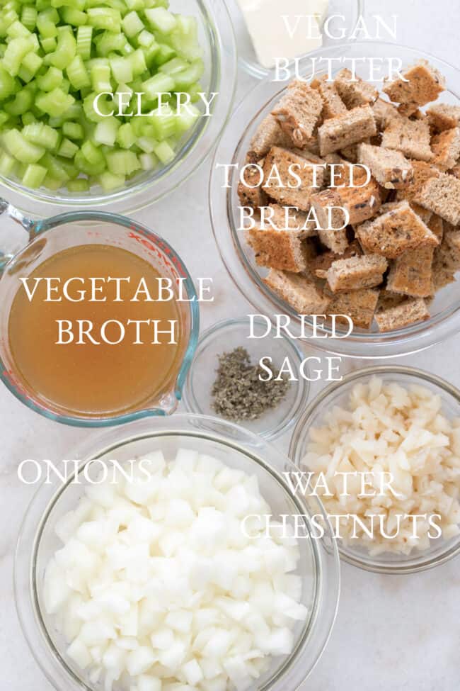 Clear bowls filled with chopped celery, cubes of toast, vegetable broth, onions and water chestnuts for a vegan stuffing recipe.