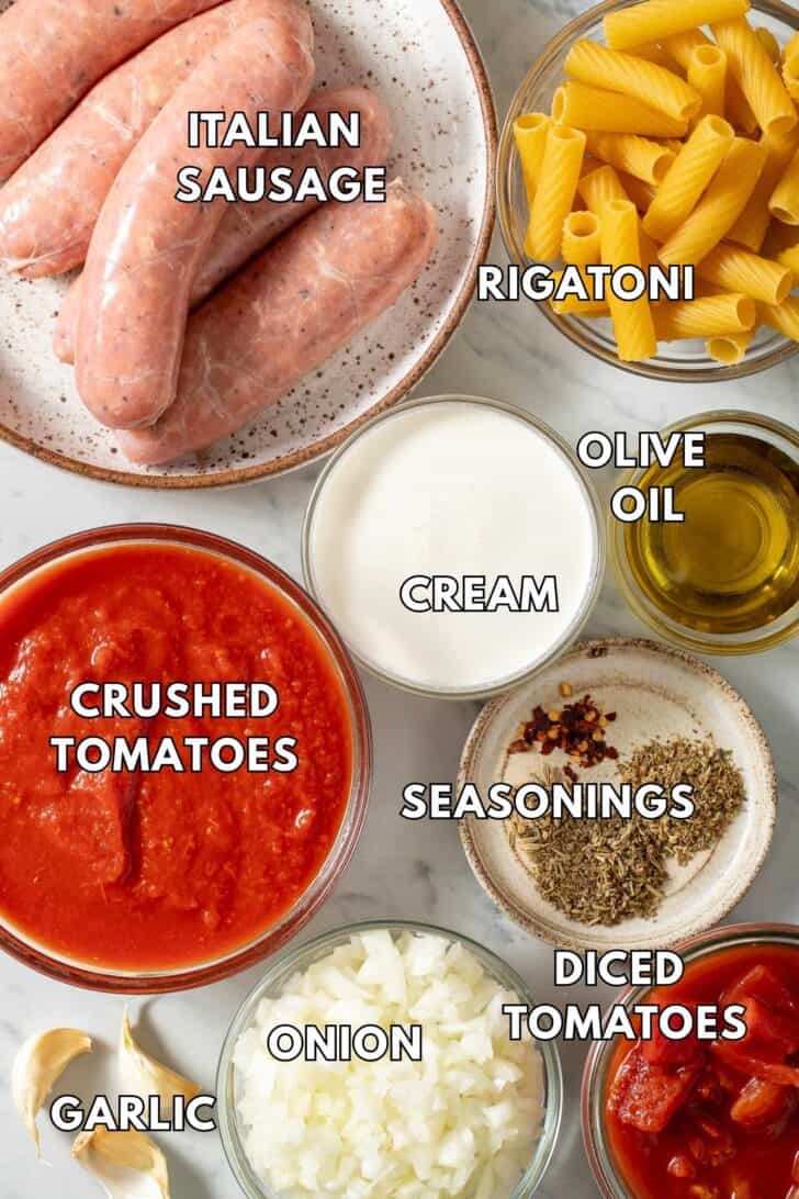 Sausage Pasta Recipe Glass bowls filled with crushed tomatoes, chopped onion, cream and Italian sausage for a sausage pasta recipe.