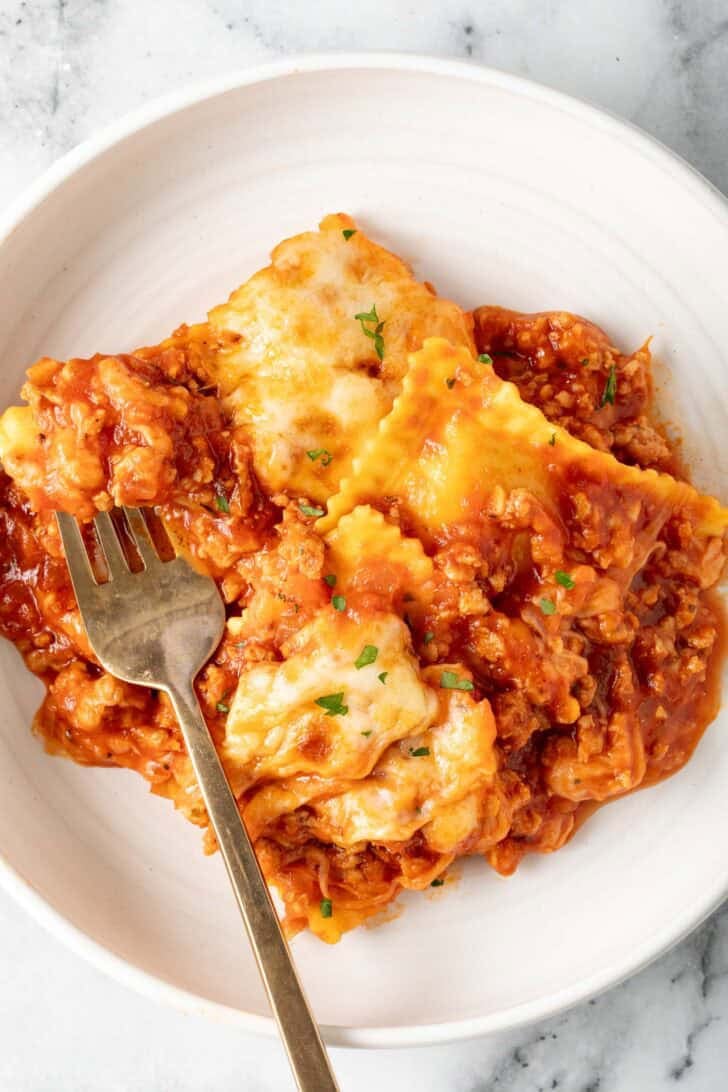 Baked Ravioli Lasagna Baked Ravioli Lasagna in a white bowl with a fork.