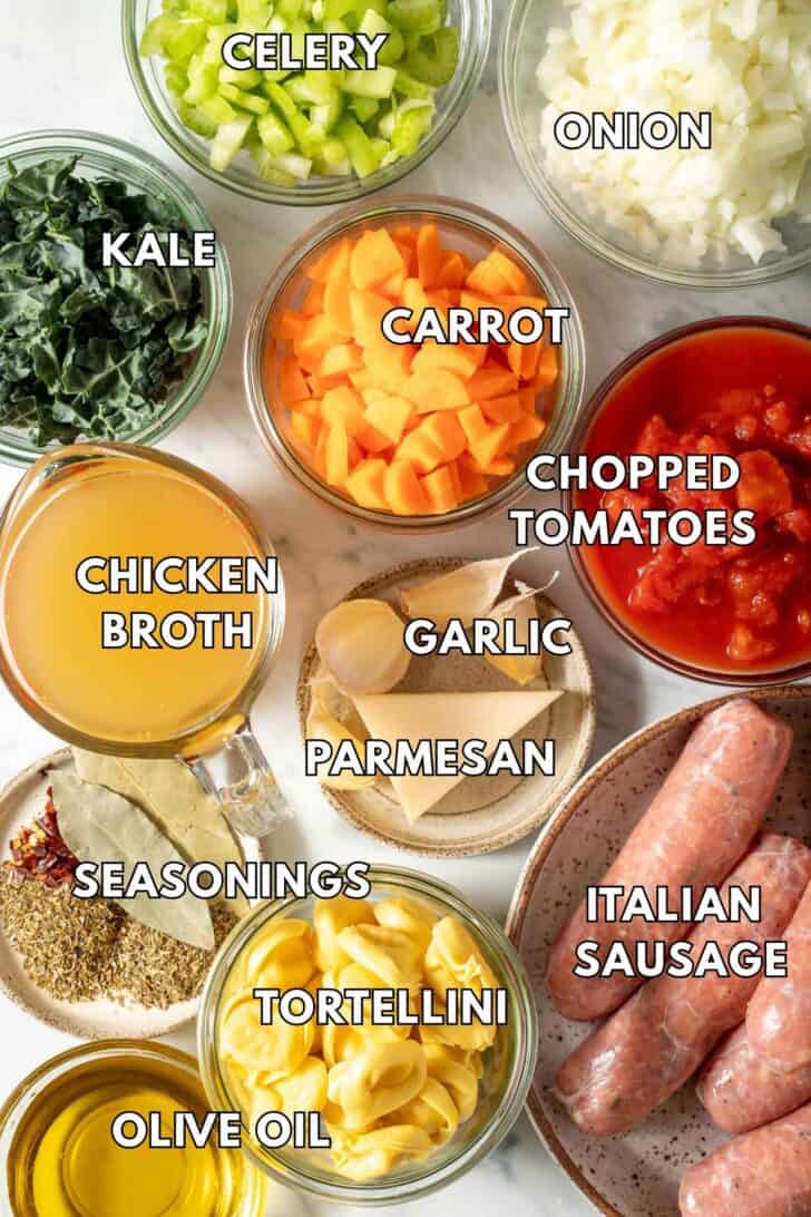 Sausage Tortellini Soup Glass bowls filled with seasoning, Itomatoes, onion, celery, chopped carrots and kale.