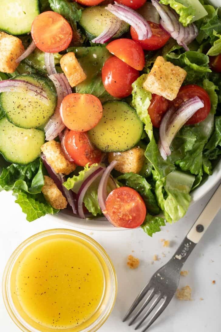 Honey Vinaigrette Salad Dressing Honey Vinaigrette Salad Dressing in a small glass bowl next to a salad in a white bowl.